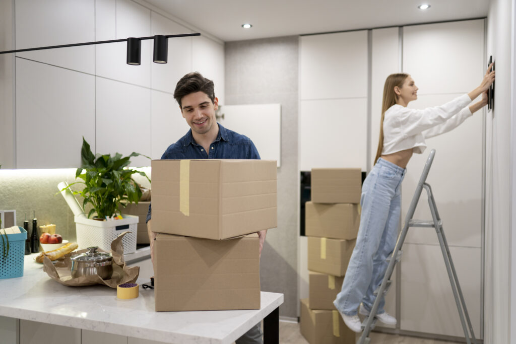 A man and woman moving boxes in a room.